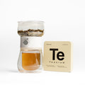 Brewed Teanium TOVLA Georgian White tea in glass infuser next to tin pocket box